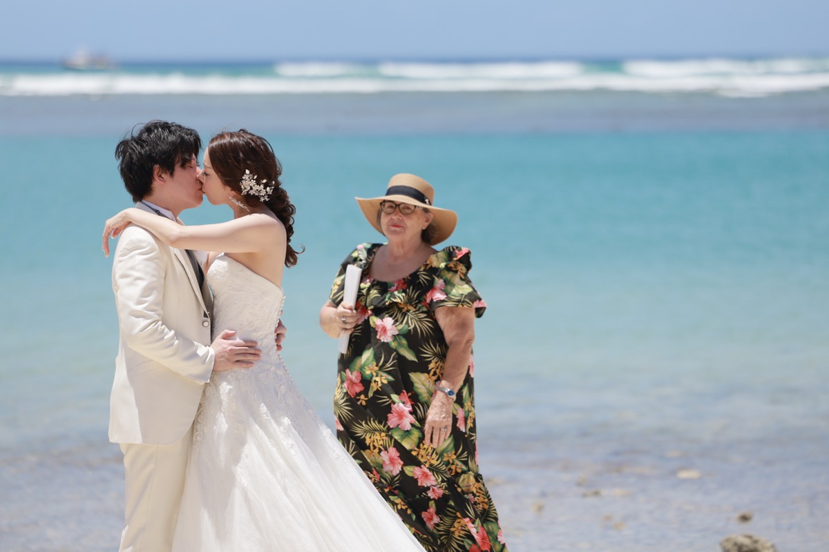 ビーチウェディングで誓いのキスを交わす新郎新婦