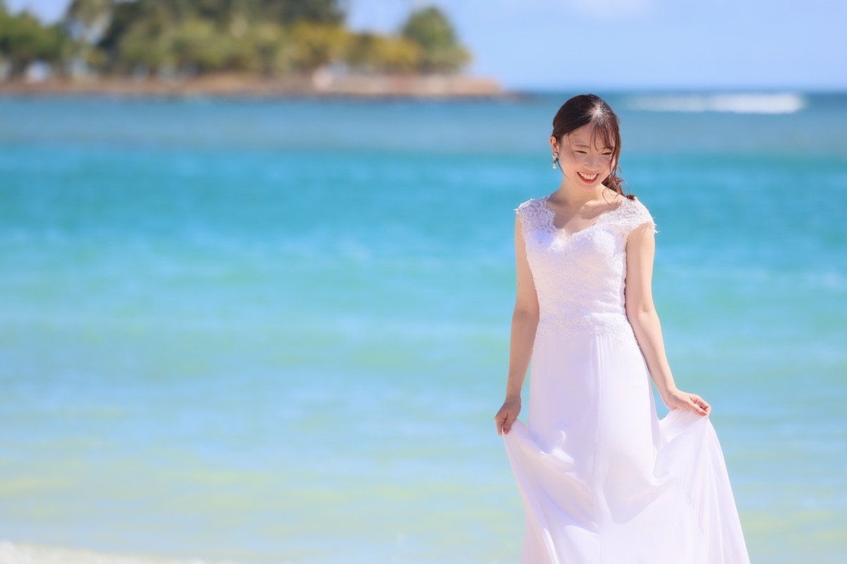 オーシャンビューのビーチでドレス姿で微笑む新婦