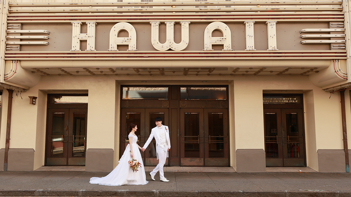 HAWAIIのロゴがある建物の前で向かい合うカップル