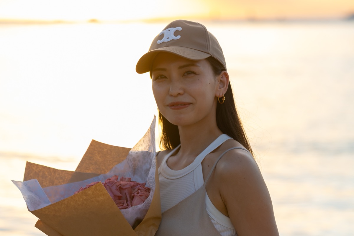 バラ12本の花束を抱えて微笑む女性