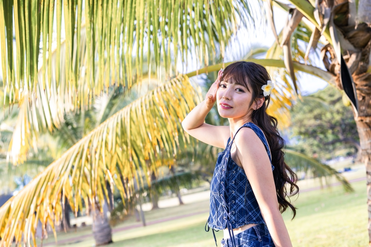 ヤシの葉の前で振り返る女性