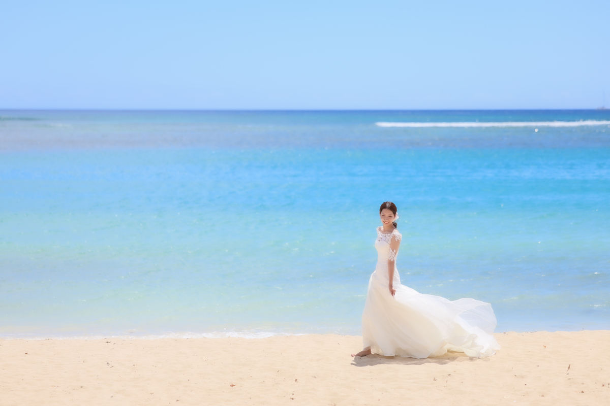 海をバックに歩く新婦