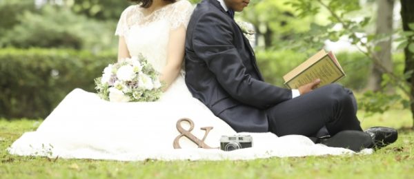 芝生の上で背中合わせで座りあう新郎新婦
