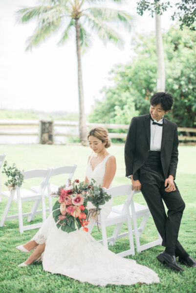ガーデンの白いチェアに腰掛ける花嫁と寄り添う新郎｜ハワイ・マウロアガーデンでのウェディングフォト撮影シーン