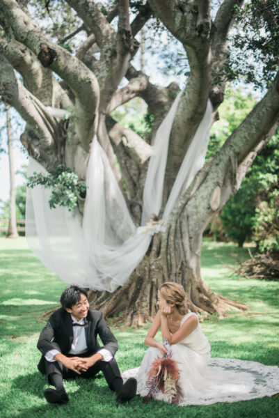 マウロアガーデンのバニアンツリーの下で寄り添うふたり｜白いヴェールが風に揺れるハワイの前撮りフォト