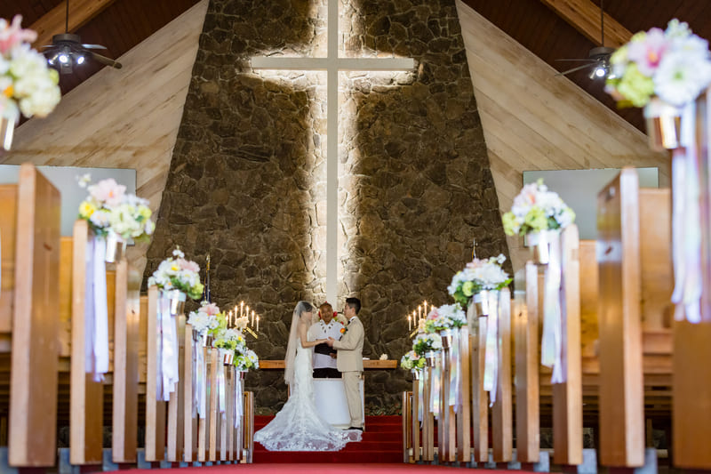 モアナルアコミュニティ教会で牧師の前に立ち誓いを交わす新郎新婦｜ハワイ教会挙式フォト